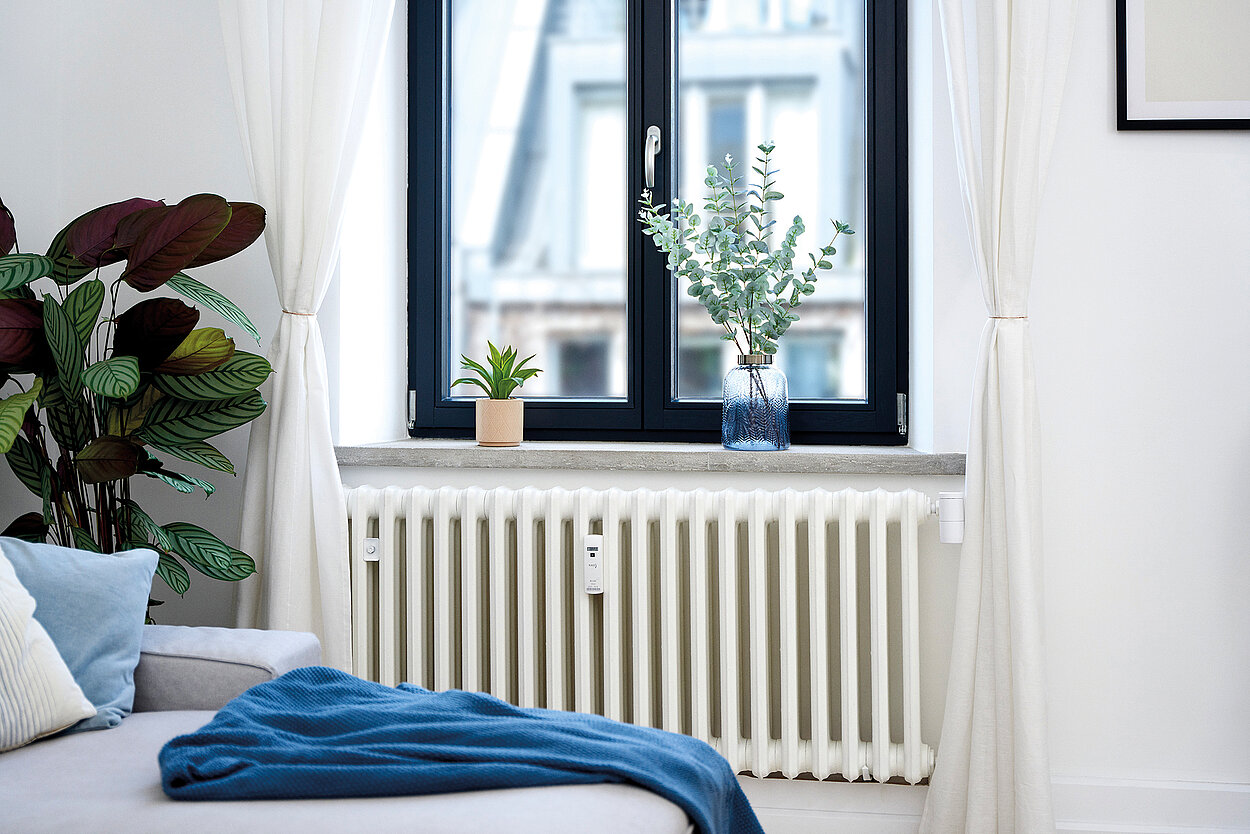 Wohnzimmer mit einem Heizkörper, einem smartes Thermostat sowie einem Heizkostenverteiler von KALO